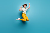 Full body photo of funky pretty lady jumping high up celebrating weekend vacation start wear casual green shirt yellow pants sneakers isolated blue color background