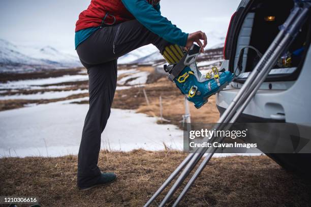 woman putting on backcountry ski boot in iceland - skischoen stockfoto's en -beelden
