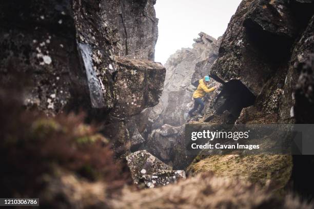 woman in yellow jacket exploring thermal fissures in iceland - grjótagjá cave stock pictures, royalty-free photos & images