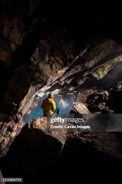 woman sitting in front of thermal pool in cave - grjótagjá cave stock pictures, royalty-free photos & images