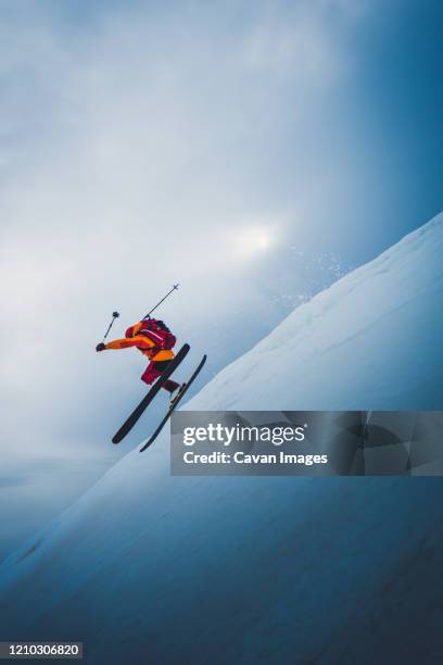 man flying off ski jump with sun and sky behind him - freestyle skiing stock pictures, royalty-free photos & images