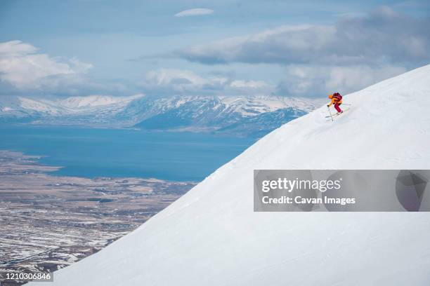 a man jumps off a ski jump on a mountain in iceland with water behind - akureyri stockfoto's en -beelden