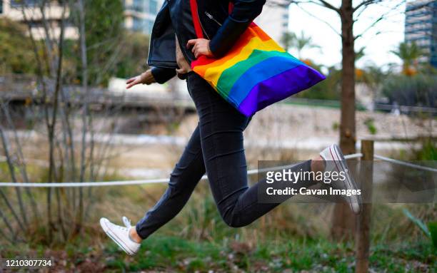 lesbian woman jumping with a pride and reusable bag. - orienteering run stock pictures, royalty-free photos & images