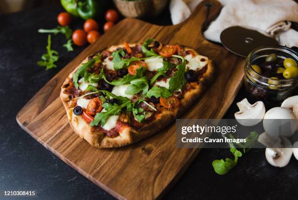 close up of handmade pizza on wooden board with ingredients around it. - focaccia azzima foto e immagini stock