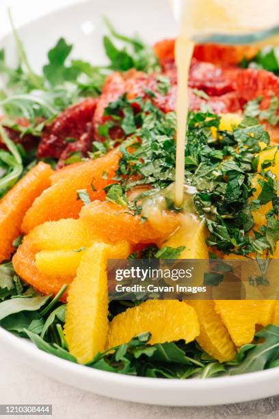 pouring vinaigrette onto citrus arugula salad - vinaigrette dressing imagens e fotografias de stock