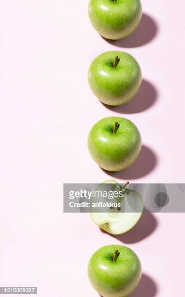 grüne äpfel in einer reihe auf rosa hintergrund - apple pattern stock-fotos und bilder