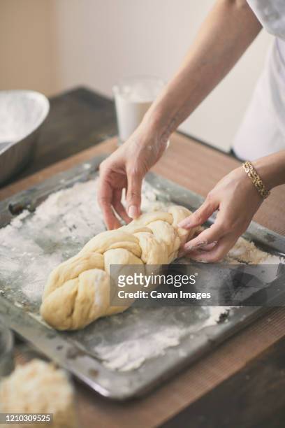 high angle view of woman preparing challah bread in tray at table - challah stock pictures, royalty-free photos & images