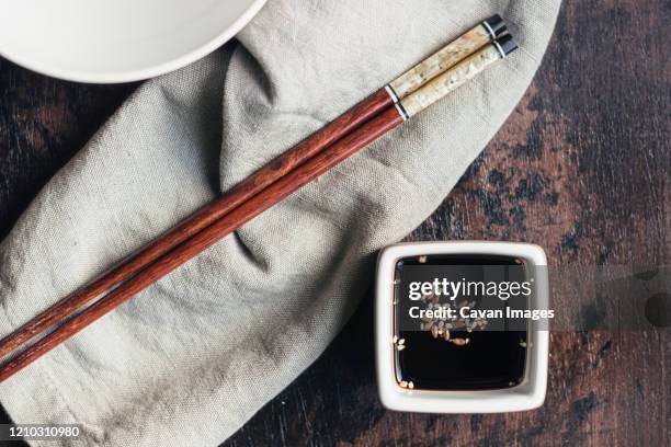 soy sauce and sesame in a vessel and bamboo chopsticks - sesam stock-fotos und bilder