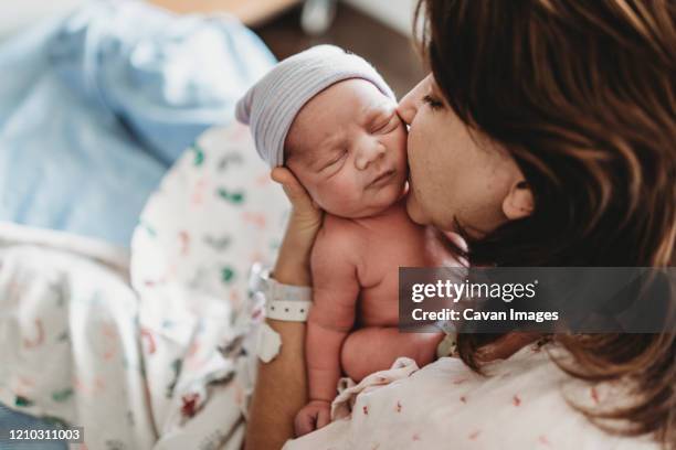close up detail of mother kissing newborn son's cheek in hospital - neugeborenes stock-fotos und bilder