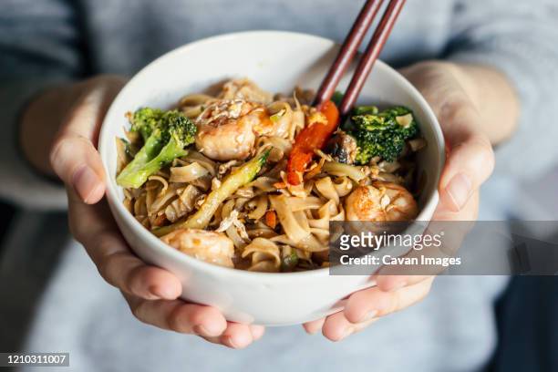 female holding a bowl of seafood thai noodles - holding chopsticks stock pictures, royalty-free photos & images