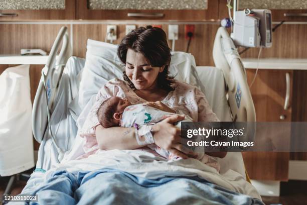 mid view of mother in hospital bed looking at newborn son - boy sitting on bed stock-fotos und bilder