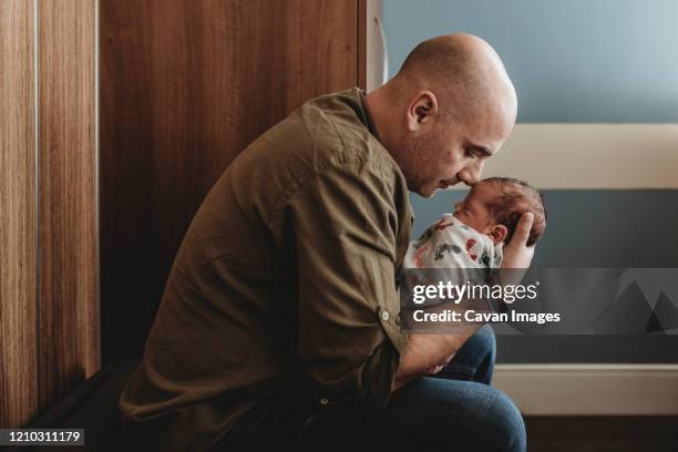 side view of happy father embracing newborn son in hospital - baby father hug side stock pictures, royalty-free photos & images