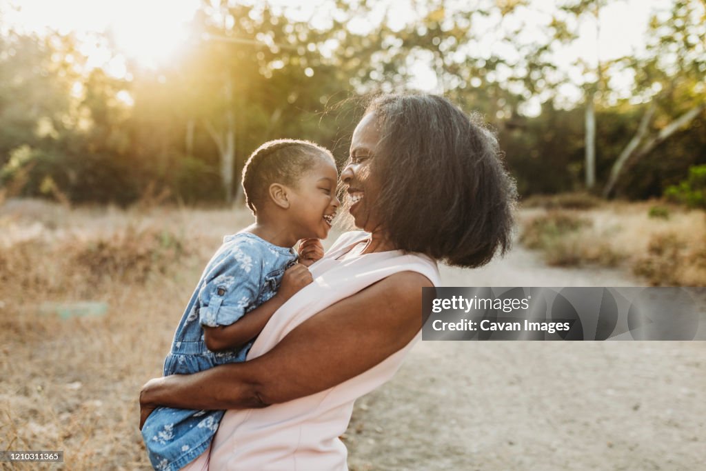 Close up of happy grandmother holding young granddaughter in sun