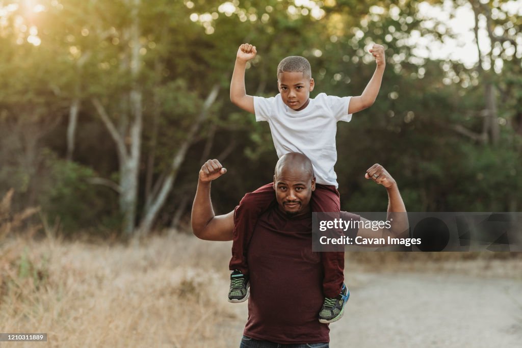 Close up portrait of school-aged son sitting on father's shoulders