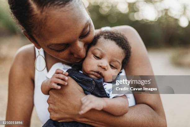 close up portrait of young mother holdiing infant daughter outside - cute black newborn babies bildbanksfoton och bilder