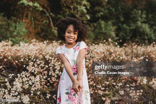 portrait of young school-aged girl smiling in field of flowers - season 13 stock-fotos und bilder