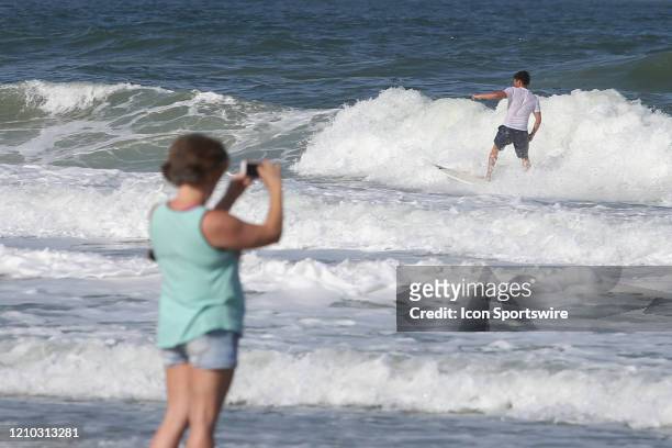 Woman photographs surfers during the beaches first open hour on April 17, 2020 in Jacksonville Beach, Fl. Jacksonville Mayor Lenny Curry opened the...
