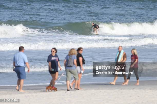 Surfer rides a wave as people gather along the beaches in its first open hour on April 17, 2020 in Jacksonville Beach, Fl. Jacksonville Mayor Lenny...