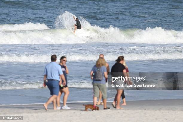 Surfer rides a wave as people gather along the beaches in its first open hour on April 17, 2020 in Jacksonville Beach, Fl. Jacksonville Mayor Lenny...