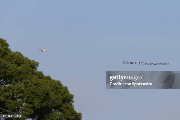 Plane carries a banner reading DO YOUR PART STAY 6 FEET APART HELP KEEP BEACHES OPEN over crowded the beaches in its first open hour on April 17,...