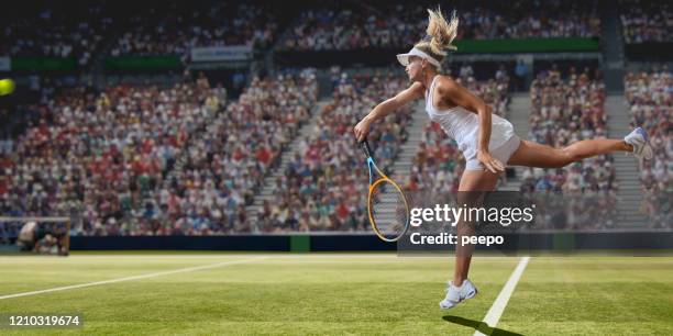 professional female tennis player serving on grass court during match - woman tennis stock pictures, royalty-free photos & images