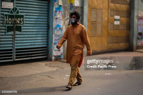 Man is crossing road wearing face masks as a precautionary act to prevent CoVid-19 from being spread. With new 341 infected people in last 24 hours,...