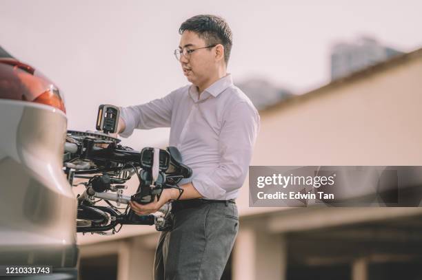 een aziatische chinese mannelijke witteboordenarbeider die klaar wordt om met zijn vouwende fiets als vervoer woon-werkverkeer te werken - folding bike stockfoto's en -beelden