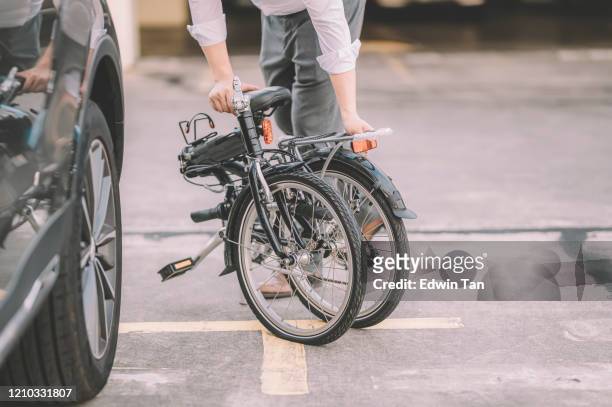 een aziatische chinese mannelijke witteboordenarbeider die klaar wordt om met zijn vouwende fiets als vervoer woon-werkverkeer te werken - opvouwbaar stockfoto's en -beelden