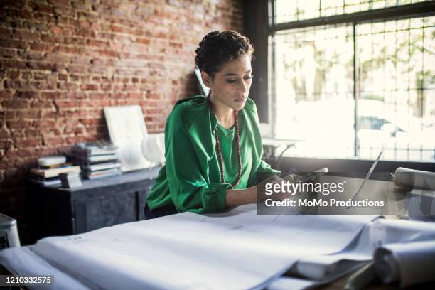 Businesswoman looking over architecture blueprints in office