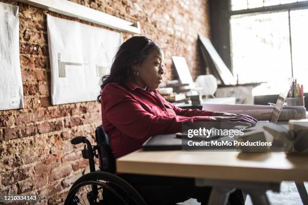 businesswoman in wheelchair working at desk - handicapped adults stock-fotos und bilder