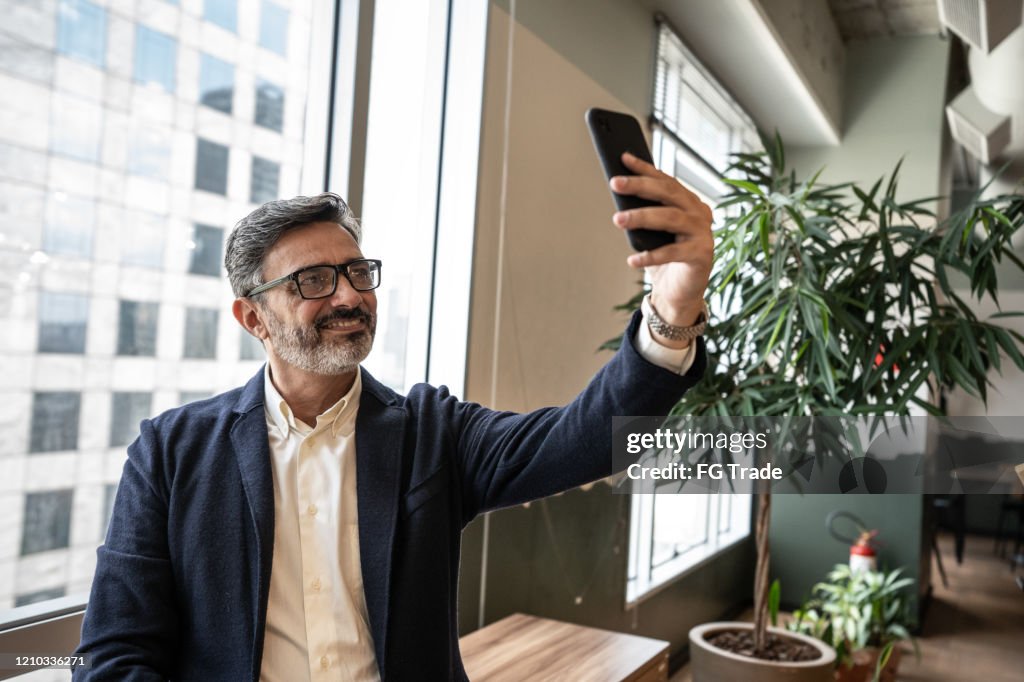 Mature businessman taking a selfie at office