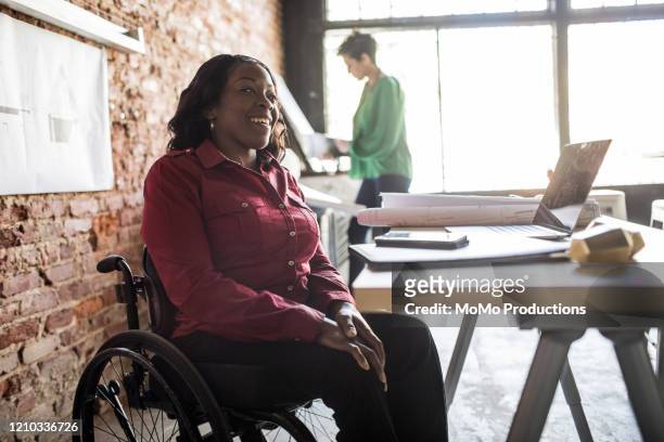 businesswoman in wheelchair working at desk - persons with disabilities stock pictures, royalty-free photos & images