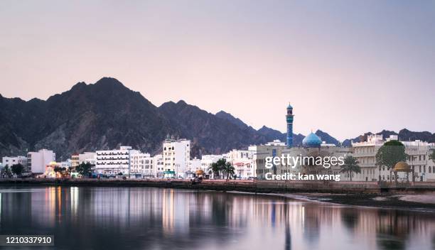 high angle view of buildings and mountains against sky - stock photo photo taken in muscat, oman - oman muscat stock pictures, royalty-free photos & images