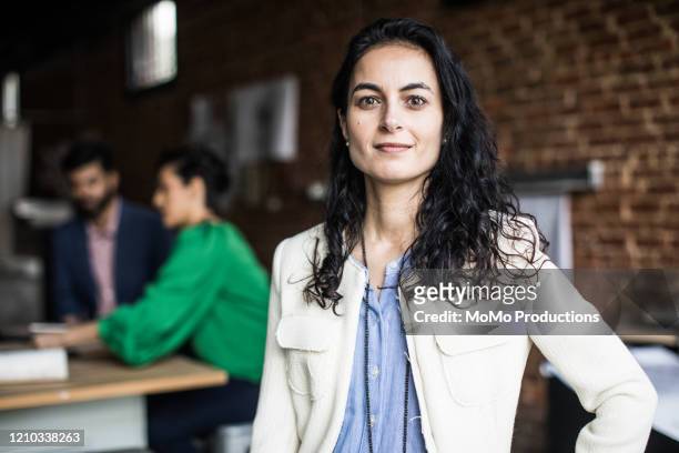 portrait of businesswoman in creative office - persona in secondo piano foto e immagini stock