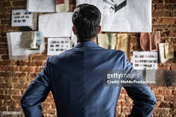 rear view of businessman looking at creative wall - rückansicht stock-fotos und bilder