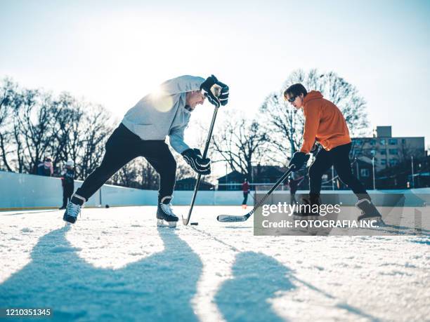 father and son playing hockey outdoors - ice rink stock pictures, royalty-free photos & images