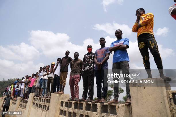 People watch the remains of Nigeria's Chief of Staff , Abba Kyari, being buried at the Gudu Cemetery in Abuja on april 18, 2020. Abba Kyari, the...