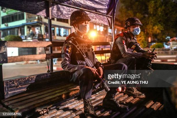Police personnel sit on a vehicle as they patrol on a road amid concerns over the spread of the COVID-19 coronavirus, in Yangon on April 18, 2020. -...