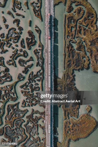 freight train crossing marshlands as seen from directly above, texas, united states of america - aerial train stock-fotos und bilder