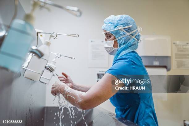 nurse washing hands at medical facility to avoid covid-19 virus. - doctor scrubs stock pictures, royalty-free photos & images
