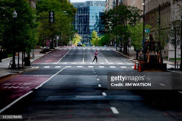 Woman runs through the empty streets in Washington, DC, on April 18 during a stay-at-home order as the coronavirus pandemic continues to hamstring...