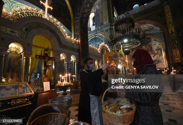 Ukrainian Orthodox priest wearing a mask blesses Easter cakes for believers in an almost empty St. Volodymyr Cathedral in Kiev on April 18 on the eve...