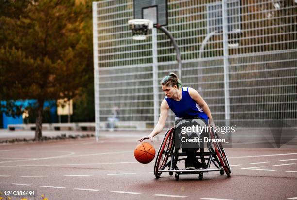 frau im rollstuhl spielt basketball - sportler mit behinderung stock-fotos und bilder