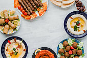 Lebanese food eaten for Ramadan eid with space for text. Middle eastern traditional cuisine including falafel, hummus, halal kebab meat, dates, Muajjanat Sabanej, muhammara and mutabal.