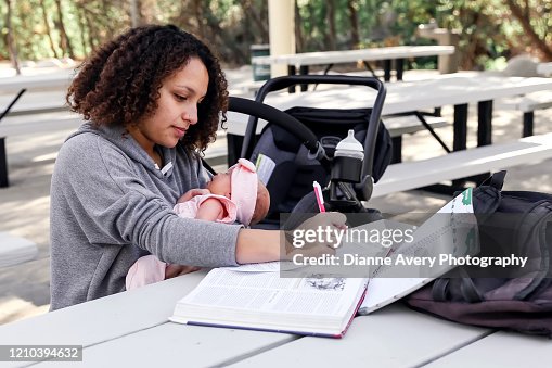 Young single mom studying for college exam while taking care of a newborn baby girl Young single mom studying for college exam while taking care of a newborn baby girl