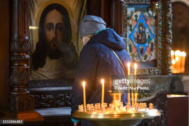 Believer wearing a protective mask stands in front of an icon in empty Volodymysky Cathedral on the eve of the Orthodox Easter service, amid the...