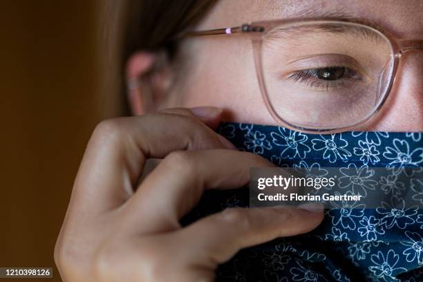 Woman wears a mouth protection on April 19, 2020 in Waldhufen, Germany. For monday on there is a requirement to wear mouth protection during shopping...