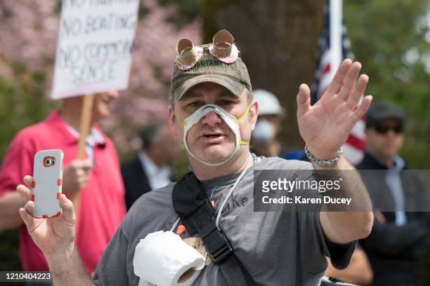 Man wearing a cutout mask gathered with hundreds of others at a 'Hazardous Liberty! Defend the Constitution!' rally to protest the stay-at-home...