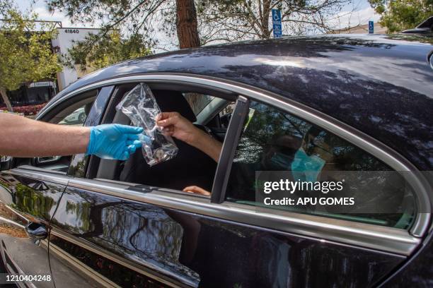 Worshippers are given communion inside their car while Pastor Tim Thompson leads an on-line Sunday Service in the Christian '412 Church Murrieta'...