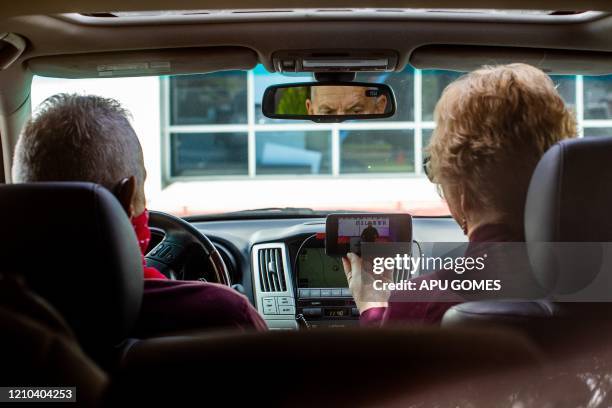 Linda Haas, and her husband Chris Haas watch an online Sunday Service by Pastor Tim Thompson at the Christian '412 Church Murrieta' parking lot on...